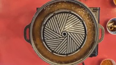 Boş metalik barbekü tavasını kömür ocağına koyun. Pirinç mangal tepsisinde pişmiş domuz eti ve etli Tayland büfesi yemeği. Japonya 'da sıcak Kore yemeği Yakiniku Barbekü