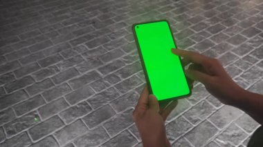 Elinde yeşil ekranlı bir telefon tutan kadın..