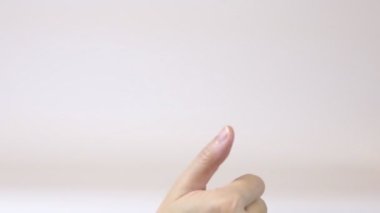 Kadın beyaz arka planda baş parmağıyla EVET işareti yapıyor. El iletişimi