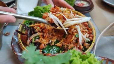Yam Naem Khao Tod Baharatlı Domuz Salatası ve Çıtır Pirinç, geri dönüştürülmüş kağıt tabakta sebze, Tayland yemeği baharatlı popüler aperatif Kızarmış pirinç ve biber ezmesi ile marine edilmiş domuz pastırması..