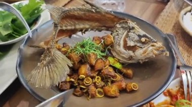 Çin restoranında servis edilen kızarmış sarımsak ve baharatlı Tayland biberiyle kaplanmış balık buğulama üzerine kızarmış balık.