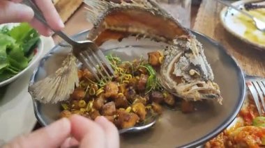 Çin restoranında servis edilen kızarmış sarımsak ve baharatlı Tayland biberiyle kaplanmış balık buğulama üzerine kızarmış balık.