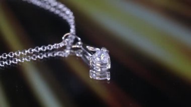 Altın sarısı arka planda, gümüş ve makro fotoğraflarla süslenmiş, beyaz altından yapılmış kalp şeklinde bir kolye.