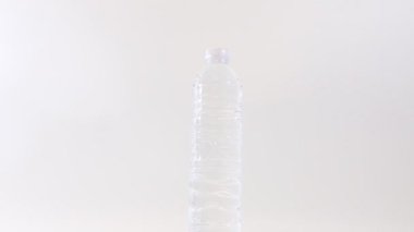 Plastik bir içki şişesini kapat. Beyaz arka plan üzerinde dönen durgun su.