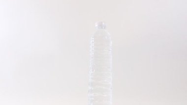 Plastik bir içki şişesini kapat. Beyaz arka plan üzerinde dönen durgun su.
