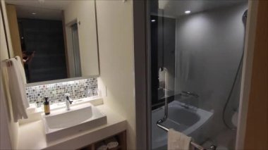 Modern bir otel banyosu. Duvarlar açık renkli fayanslarla süslenmiş..