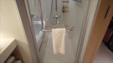 Modern bir otel banyosu. Duvarlar açık renkli fayanslarla süslenmiş..