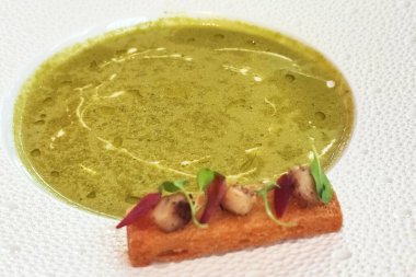 restoranda beyaz bir tabak üzerinde croutons bezelye çorbası