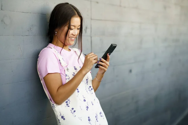 Mulher Asiática Positiva Usando Seu Smartphone Com Uma Caneta Caneta — Fotografia de Stock