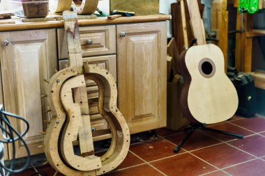 İspanyol flamenko gitarı yapmak için yukarıdaki ahşap kalıptan, bitmemiş gitarın yanına profesyonel Luthier atölyesindeki dolapların yanındaki fayanslı duvara yerleştirilmiş..