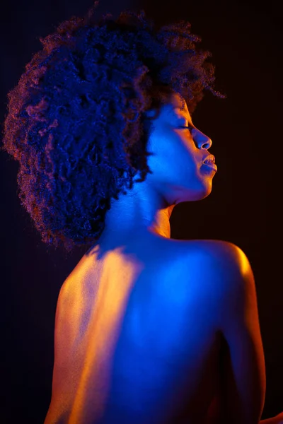 黑色背景下橙色和蓝色霓虹灯下的非洲裔美籍女性 有着非洲式的闭眼 — 图库照片