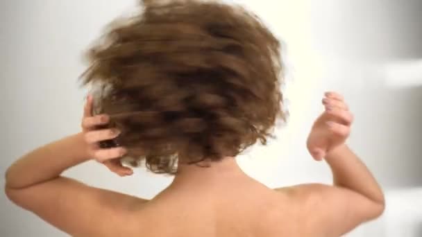 魅力的な若い女性モデル 巻き毛と 彼女の頭の上に彼女の手で再生しながら カメラを見て 裸の肩を持つ白人女性 — ストック動画