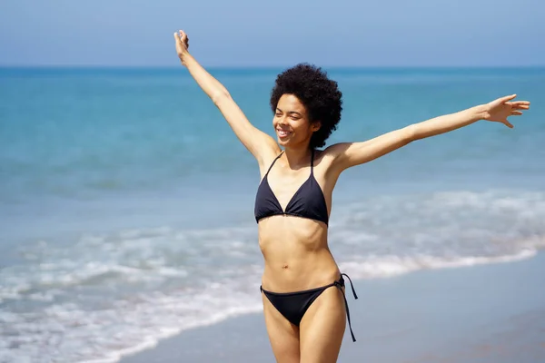 穿着泳衣的非洲裔美国女性游客在热带旅游胜地海滨散步 张开双臂 享受着自由 — 图库照片