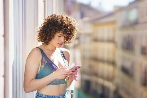 Positive Young Female Bra Jeans Curly Hair While Browsing Smartphone — Stock Photo, Image