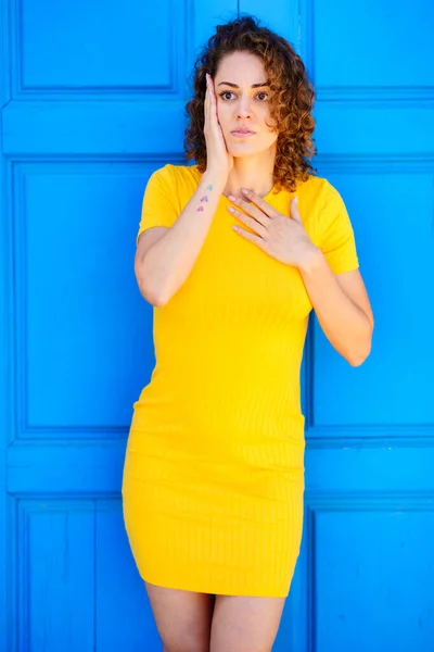 Zdumiewająca Młoda Kobieta Żółtej Sukience Kręconymi Brązowymi Włosami Trzymająca Rękę — Zdjęcie stockowe