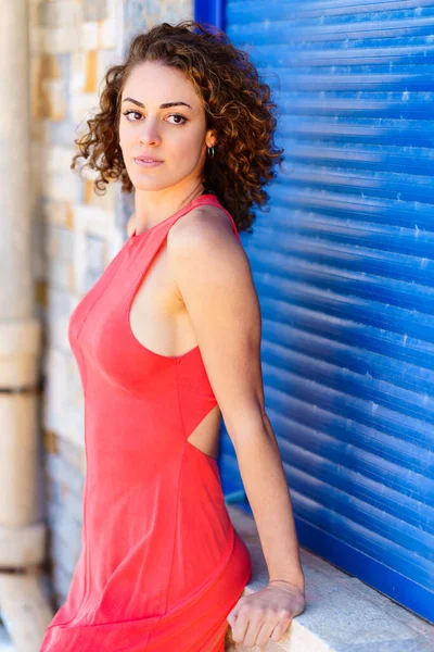 Kırmızı Elbiseli Güzel Bir Kadın Gün Işığında Mavi Panjurlara Yaslanarak — Stok fotoğraf
