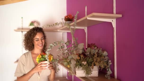 Щаслива Молода Жінка Прикрашає Вітальню Полицями Свого Будинку Квітковими Прикрасами — стокове відео