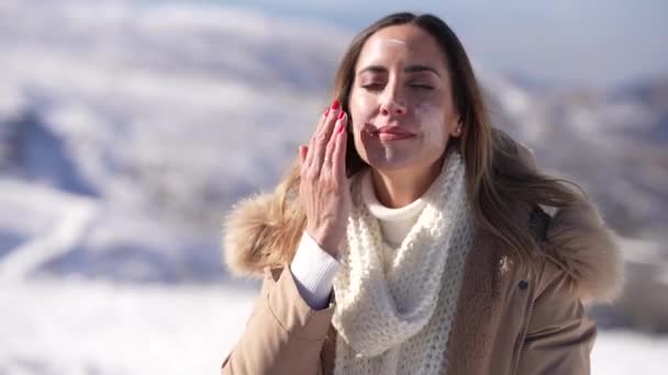 Μεσήλικη Γυναίκα Που Εφαρμόζει Αντηλιακό Στο Πρόσωπό Της Χιονισμένα Βουνά — Αρχείο Βίντεο