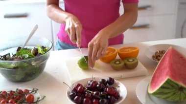 Salata ve karpuzlu kirazlara karşı güvertede limon doğrayan kadın yavaş hareket ediyor.