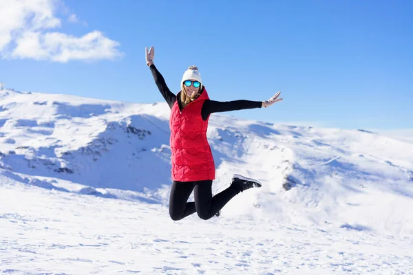 따뜻한 행복한 여성은 하늘에 대하여 구부러진 다리와 공중에 뛰어하면서 카메라를보고 — 스톡 사진