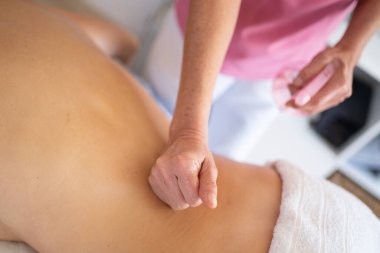 Klinikteki rehabilitasyon sırasında hastanın sırtına masaj yapan anonim terapistten.