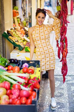 Markette meyve ve sebzelerle dikilirken, eli gözlüklü şık ve şık bir kadın manavdı.