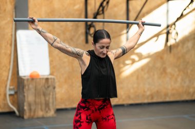 Yetişkin bir kadın spor salonunda bar ile ısınıyor.