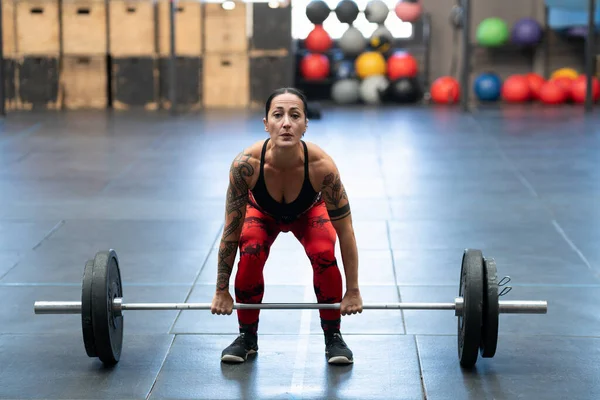 Frontal photo of a mature modern woman dead-lifting in a cross training gym alone