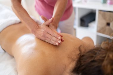 Anonim kadın osteopat modern rehabilitasyon kliniğinde masaj sırasında özel tekniği olan bir hastanın sırtını yoğuruyor.