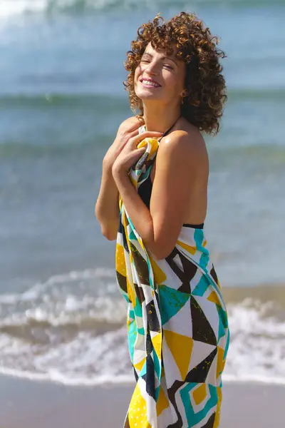 海岸に立ってカラフルなドレスでカラフルな髪の幸せな若いセンセーショナルな女性の側面ビューとカメラを見る — ストック写真