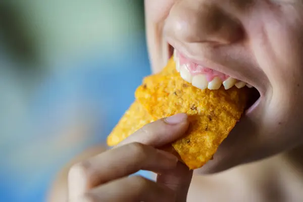 自宅でおいしいメキシコのトルティーヤチップを噛む作物認識できない10代の少女の上から ストック写真