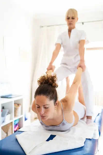 관절을 고치는 누워있는 여자의 당기는 Osteopath 로열티 프리 스톡 사진