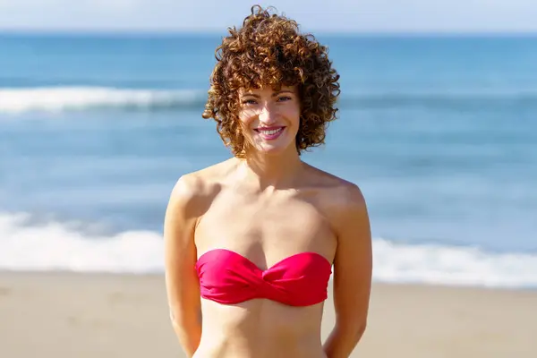 꼬부라진 미소와 카메라를 비키니에 여성의 초상화 흔들리는 해변에 스톡 이미지