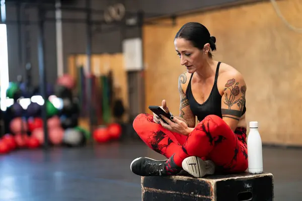 Mulher Madura Esportiva Usando Telefone Celular Relaxado Ginásio Treinamento Cruzado — Fotografia de Stock