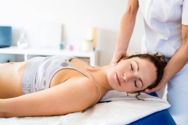 Fizyoterapist hastane odasında boyun masajı yaparken kadın hasta manuel terapi kliniğinde tedavi görüyor.