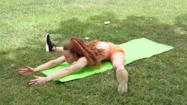 Bir kadın yeşil yoga minderinde olağanüstü bir güç ve esneklik sergiliyor. Form ve ahengi vurguluyor. Zarif hareketleri atletizmi ve soğukkanlılığı gösteriyor.