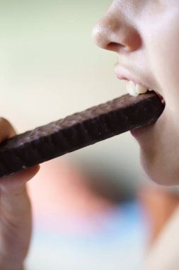 Evde çikolatalı protein yiyen tanınmayan genç bir kızın yan görüntüsü.