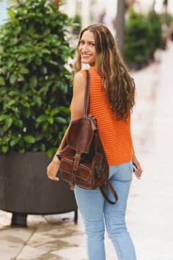 Güzel bir Latin kadının dikey portresi. Dışarıda yürürken gülümsüyor.