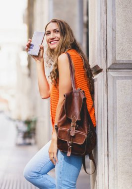 Elinde cep telefonu olan ve gülümseyen Latin güzellerinin dikey fotoğrafı.