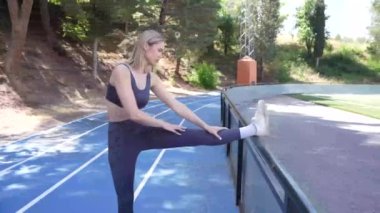 Genç bir kadın, ağaçlarla çevrili bacaklarını açarak sakin bir ortamda aktif bir yaşam tarzı sergiliyor. Bu görüntü, doğal bir ortamda uygunluğu ve esnekliği teşvik eder.