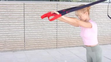 Bir kadın direniş bandıyla dışarıda esneme egzersizleri yapıyor. Fitness, kuvvet ve esneklik eğitimi yoluyla aktif ve sağlıklı yaşam tarzını gösteren ayrıntılı adım rehberi