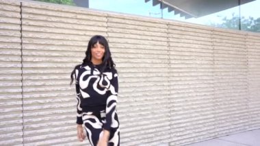 Sokakta dans eden genç siyahi kadın, çok gösterişli kıyafetler giyiyor. Gençlik hayatı ve iyi titreşimler kavramı.