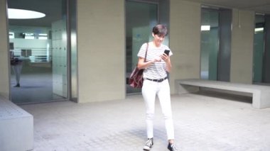 Canlı bir ortamda, şık genç bir insan akıllı telefonunu kullanarak günümüzün yenilikçi toplumunun rahat, teknolojik yaşam tarzını somutlaştırarak bilerek yön bulur.