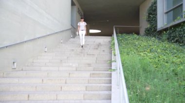 Şık bir insan modern bir merdiven iniyor, yemyeşil bir ortamda, huzur ve sükuneti teşvik eden sakin bir açık alanda çağdaş mimarinin güzelliğini vurguluyor.