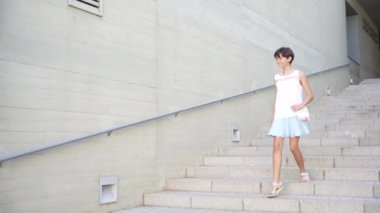 Genç bir kadın zarif bir şekilde, çevrenin genel güzelliğini artıran yemyeşil bir yeşil alanla çevrili, gösterişli, modern bir mimari alanda zarif bir şekilde tasarlanmış bir dizi merdiven iniyor.