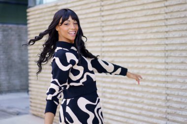 Neşeli güzel İspanyol kadın dansçı enerjik bir şekilde dönüyor ve şehirde kameraya gülümsüyor.