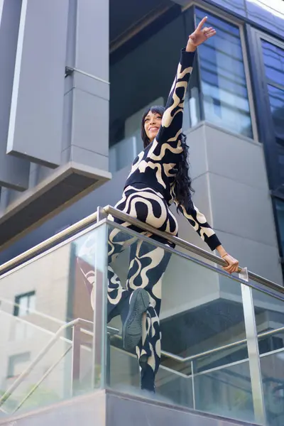 stock image Vertical low angle view of a chic woman pointing the horizon from a rail in a skyscraper