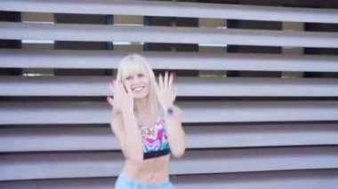 Egzersiz kıyafeti giymiş enerjik bir kadın modern bir arka plana karşı dans ediyor, canlı, eğlenceli ve aktif bir yaşam tarzını somutlaştırıyor. Sahne canlılık, ifade gücü ve hareket hissi yayar.