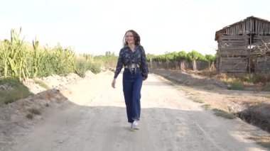 Genç bir kadın, canlı üzüm bağları ve kırsal manzarayla çevrili tozlu bir patika boyunca sakin bir yürüyüş yapar. Mükemmel bir an yaratır. Doğada sıcacık bir kucaklama.