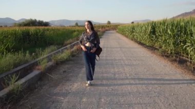 Genç bir kadın neşe ve sükunet bulur ve huzurlu bir yürüyüş yapar. Çevresi canlı, yemyeşil ve kırsal kesimlerde yavaşça yuvarlanan tepelerle çevrili, manzaralı çakıllı bir yolda.